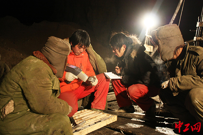 萬(wàn)建領(lǐng)（左二）針對(duì)鉆機(jī)取出的巖心進(jìn)行野外快速分析測(cè)試、